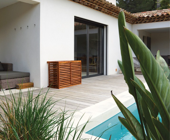 Protection décoclim appuyée à une façade de maison blanche avec une piscine en premier plan.